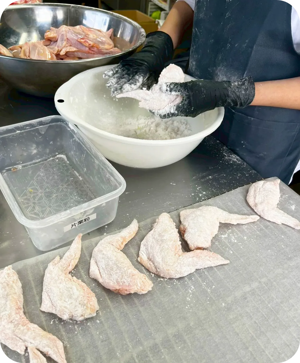 手羽先に粉をまぶして、揚げ物の下地を作る様子